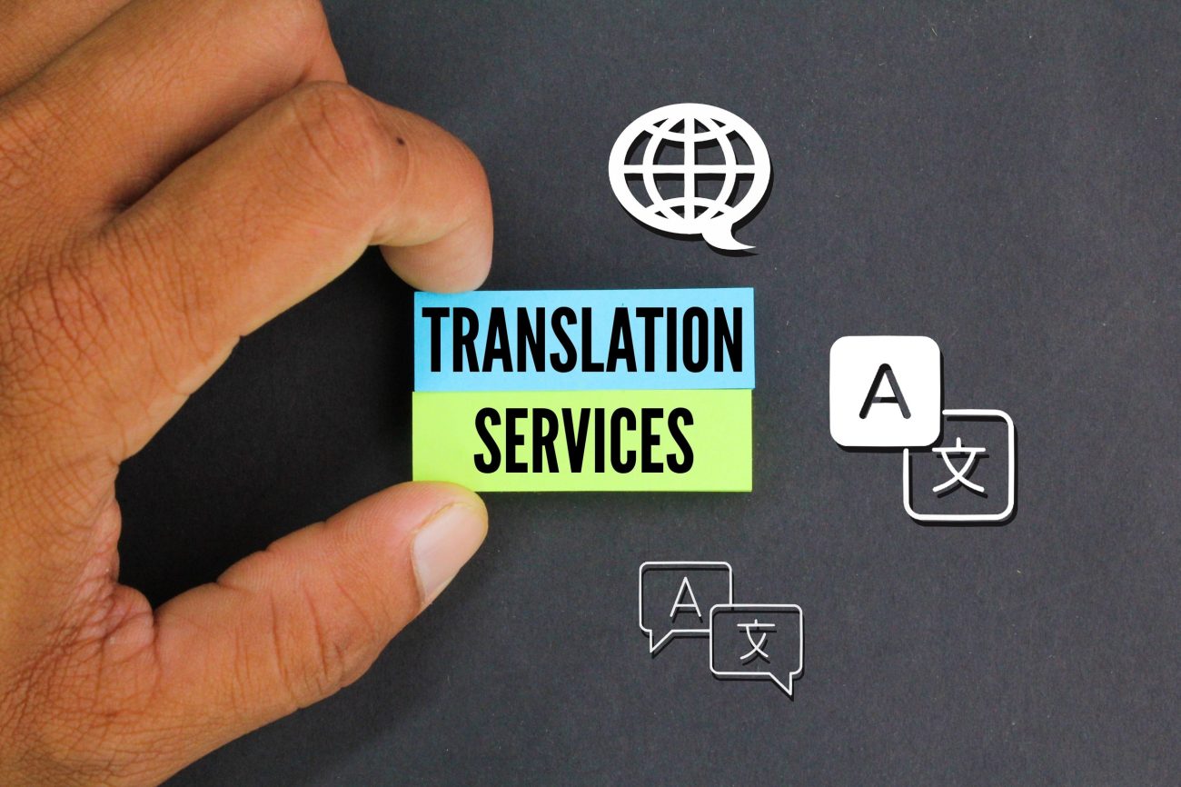 hand holding colored paper with icon and word Translation Services | Hablemos de Marketing