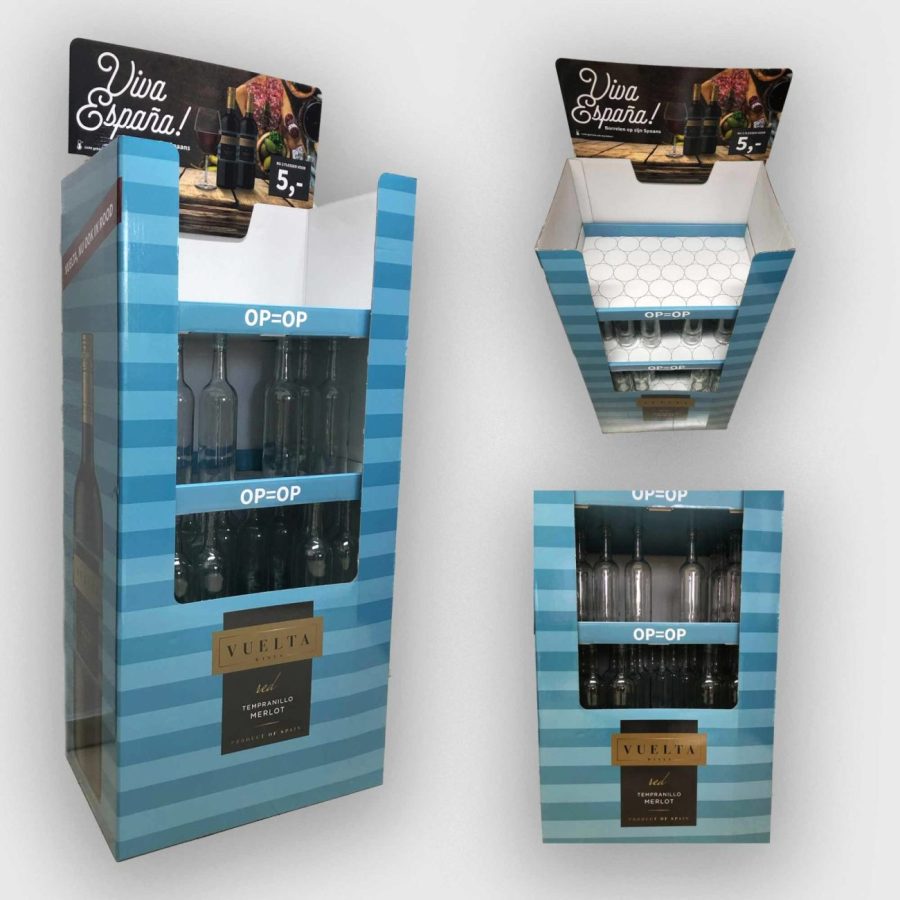 774160 - Letro | Hablemos de Marketing Three blue striped bottle display stands (one tall left, two smaller on the right) showing glass bottles and VUELTA branding for in-store promotion.